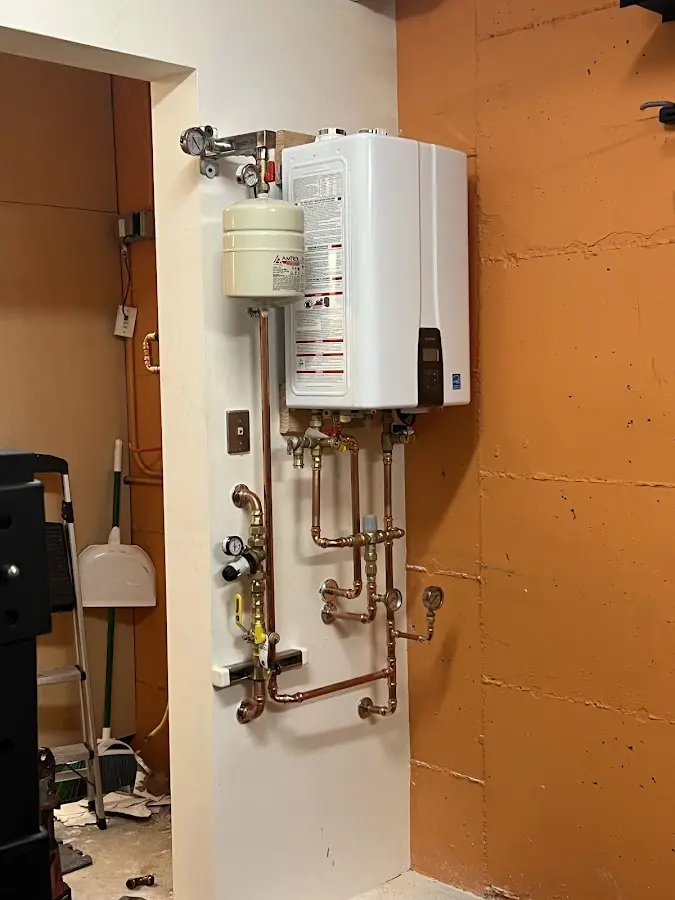 Plumbing technician inspecting water heater connections in St. Paul